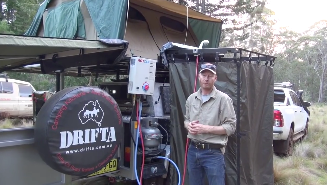 Man standing beside a HOTTAP and shower tent on a Drifta DOT camper trailer