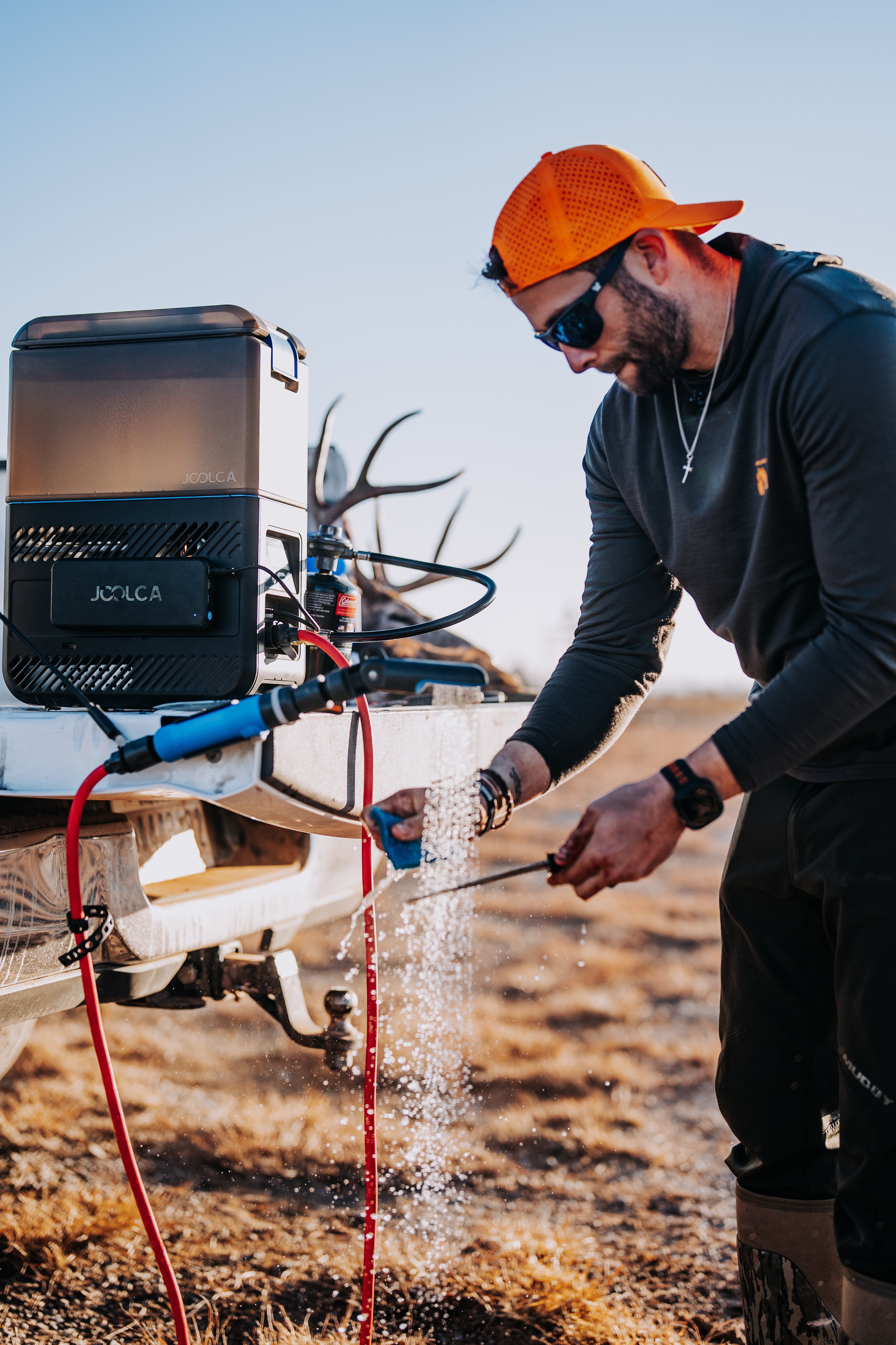 Man in hunting gear using a device on a deer mount outdoors